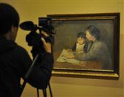 一名摄像记者在中国美术馆拍摄展出的秦宣夫1942年创作的布面油画《母教》